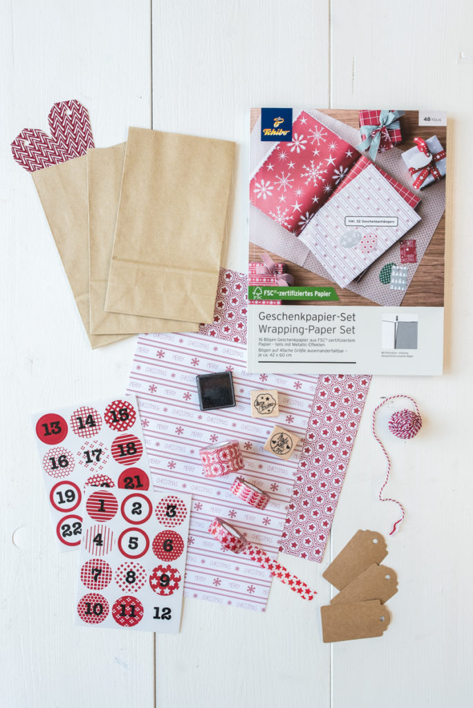 selbst gemachter DIY Adventskalender in einer Holzkiste mit Tüten, Washi Tape und Bändern von Tschibo in Naturtönen und Rot 