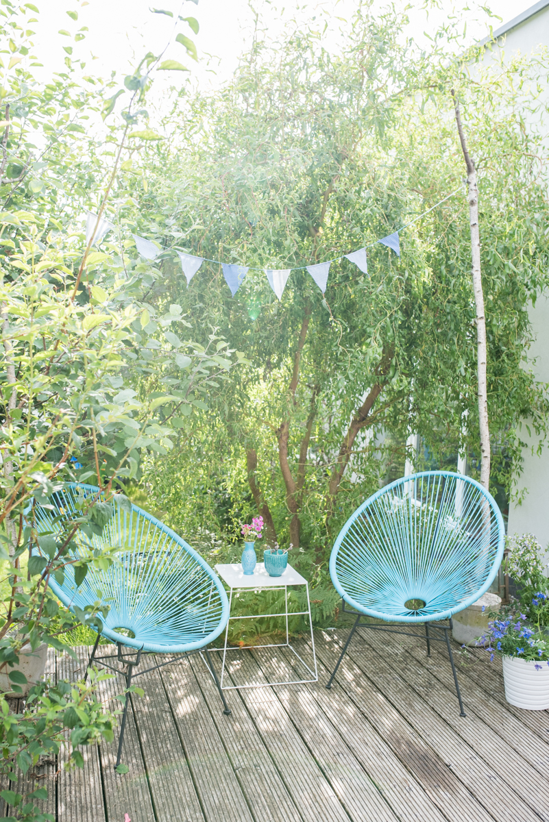 Deko im Garten mit Acapulco Chairs, Wimpelgirlande und kleiner Sitzecke im Grünen
