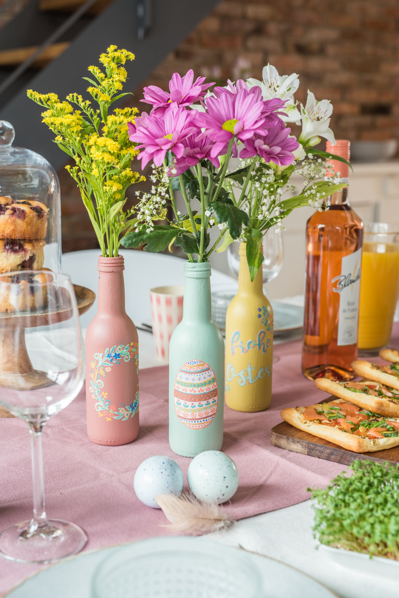 DIY Anleitung für selbstgemachte upcycling Vasen aus Weinflaschen in Pastellfarben als Tischdeko zu Ostern
