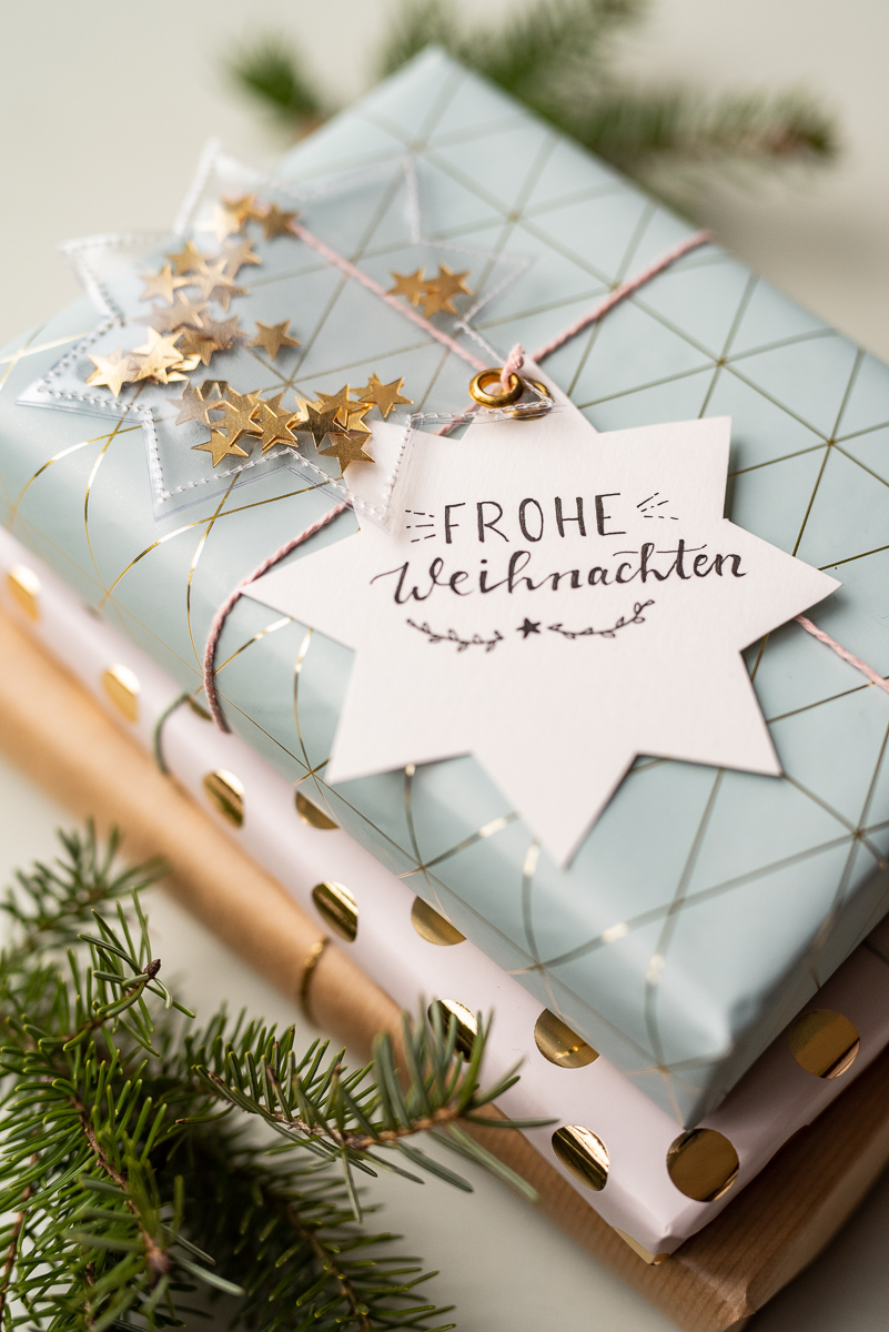 Anleitung für selbst gemachte DIY Geschenkanhänger aus Wachstuch mit Glitzer und Sternen als schöne Verpackung für Geschenke zu Weihnachten