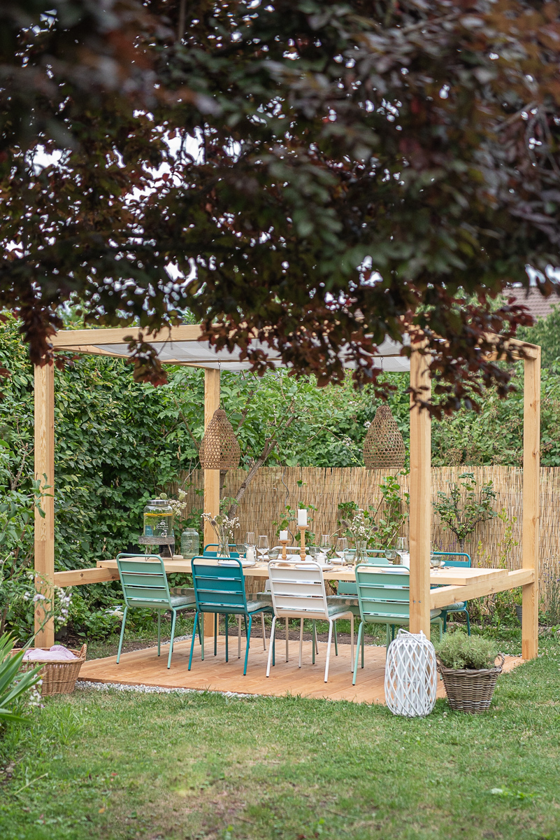 Selbst gebauter überdachter DIY Sitzplatz im Garten mit Tisch und Metallstühlen im Ibiza Look