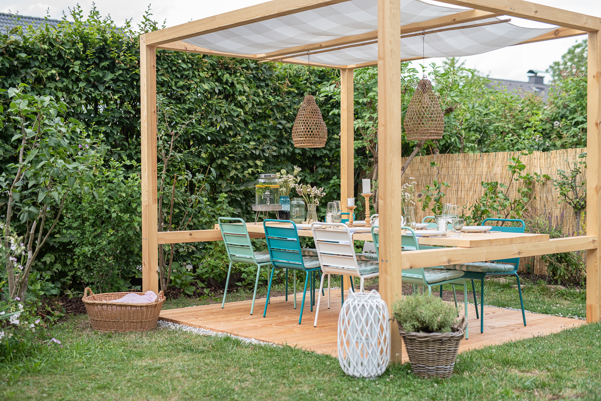 Selbst gebauter überdachter DIY Sitzplatz im Garten mit Tisch und Metallstühlen im Ibiza Look