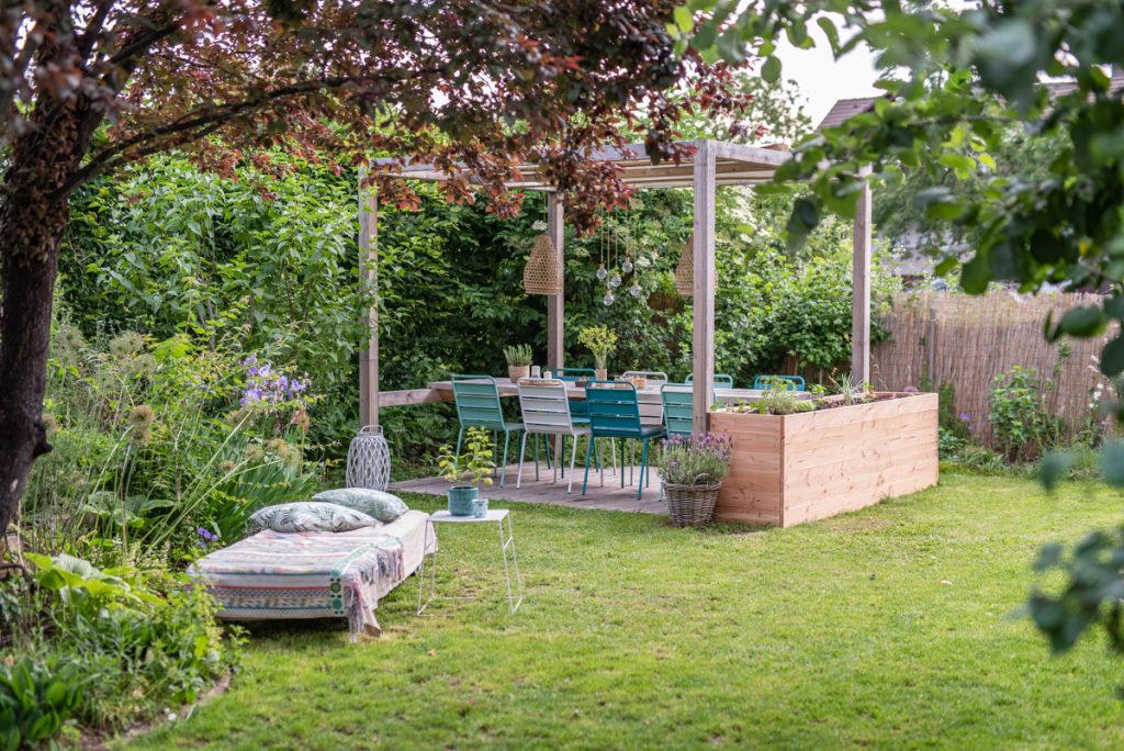 Selbst gebauter Sitzplatz im Garten mit Überdachung und Deko in Grüntönen für den Garten im natürlichen Boho Look